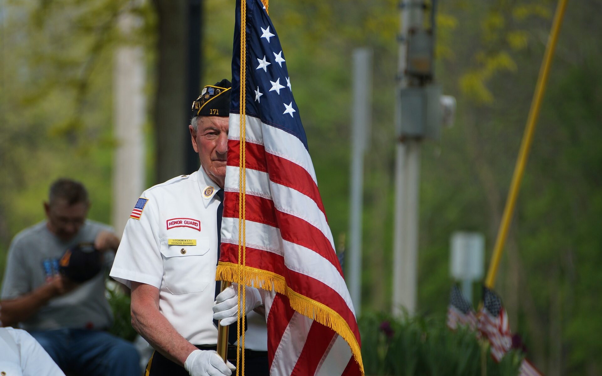 old veteran standing behind american flag at memorial day ceremony